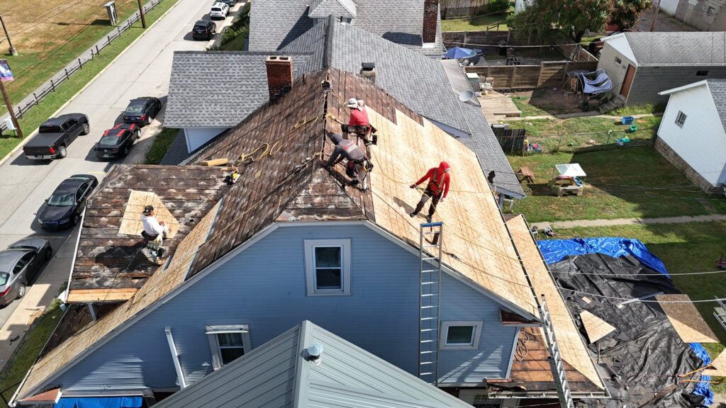 A group of workers are repairing the roof of a two-story house