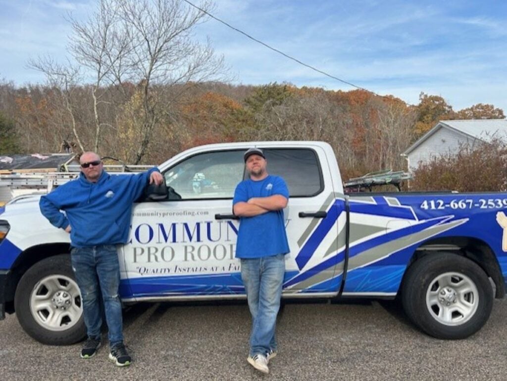 how to tarp a roof Community Pro workers Two men in blue shirts stand next to a blue and white pickup truck with "Community Pro Roofing" and a phone number on the side. Trees and houses are visible in the background.